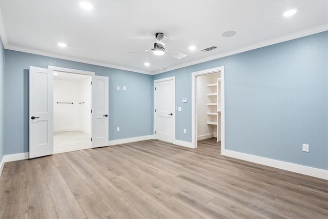 unfurnished bedroom with ceiling fan, a closet, a spacious closet, and light wood-type flooring