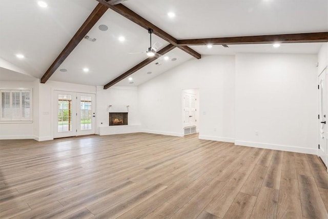 unfurnished living room with ceiling fan, vaulted ceiling with beams, a fireplace, and light hardwood / wood-style floors