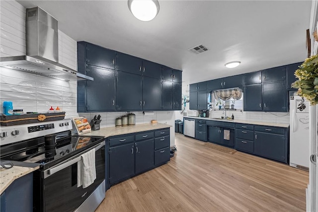 kitchen featuring visible vents, blue cabinets, appliances with stainless steel finishes, wall chimney exhaust hood, and a sink