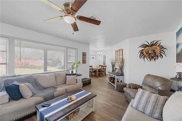 living room with wood finished floors, visible vents, and ceiling fan