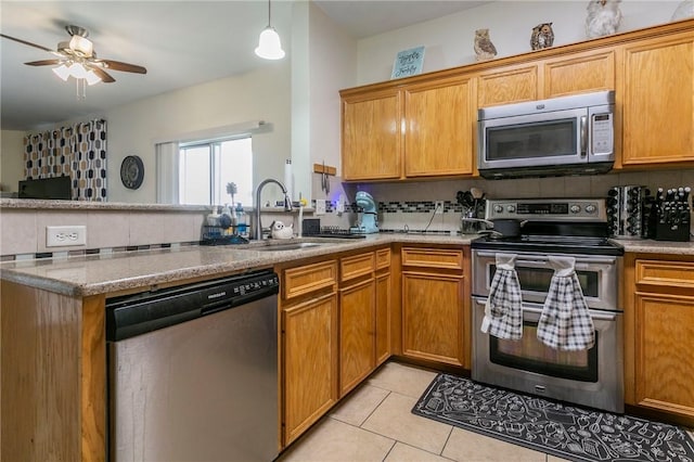 kitchen featuring light tile patterned floors, a peninsula, a sink, appliances with stainless steel finishes, and tasteful backsplash