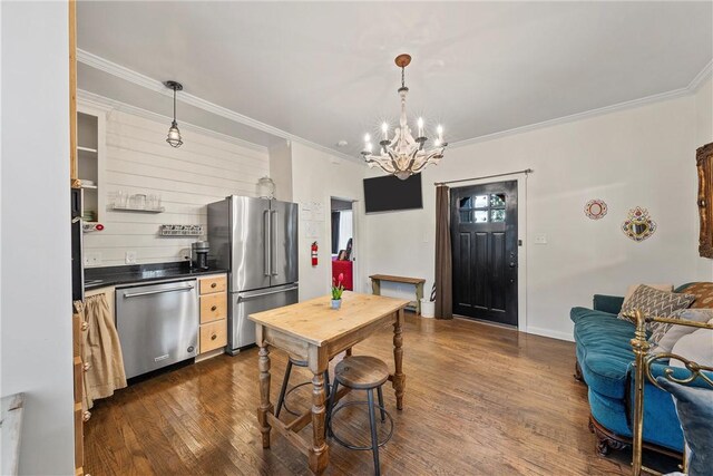 kitchen featuring dark hardwood / wood-style floors, ornamental molding, stainless steel appliances, and a chandelier