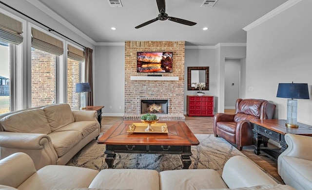 living room featuring ornamental molding, ceiling fan, a fireplace, and light hardwood / wood-style flooring