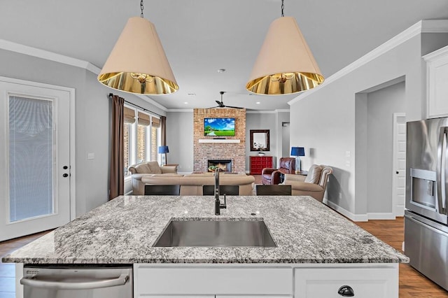 kitchen featuring sink, stainless steel appliances, light stone countertops, a kitchen island with sink, and white cabinets