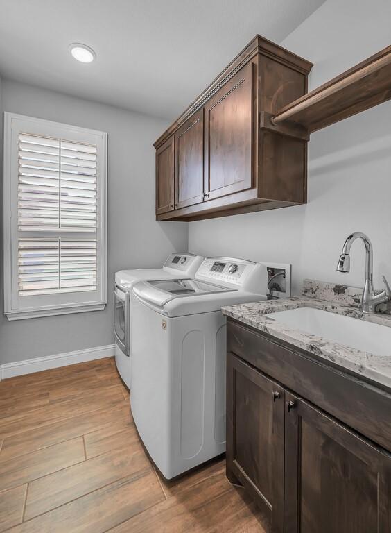 laundry room featuring cabinets, separate washer and dryer, sink, and light hardwood / wood-style floors