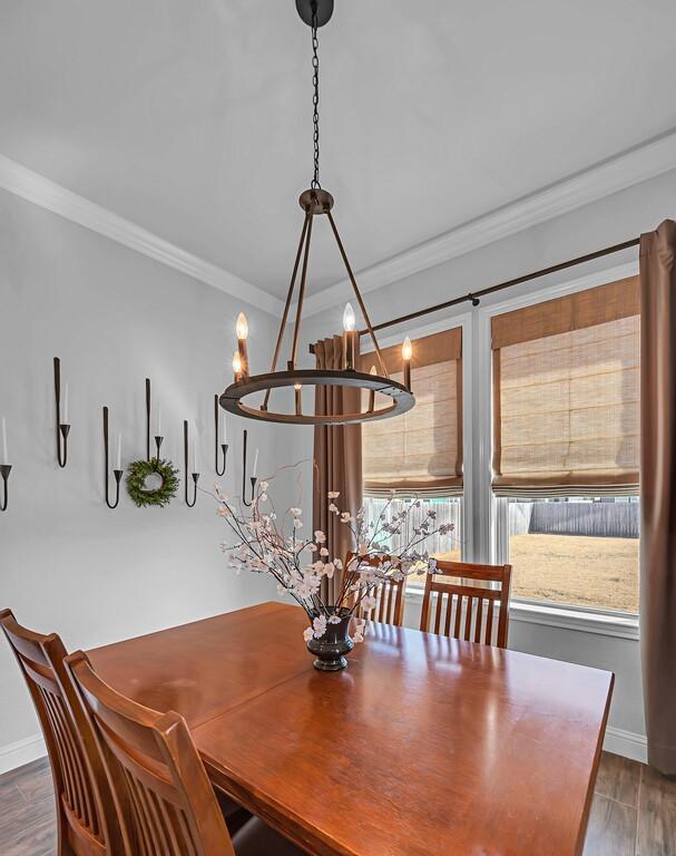 dining area with crown molding and dark wood-type flooring