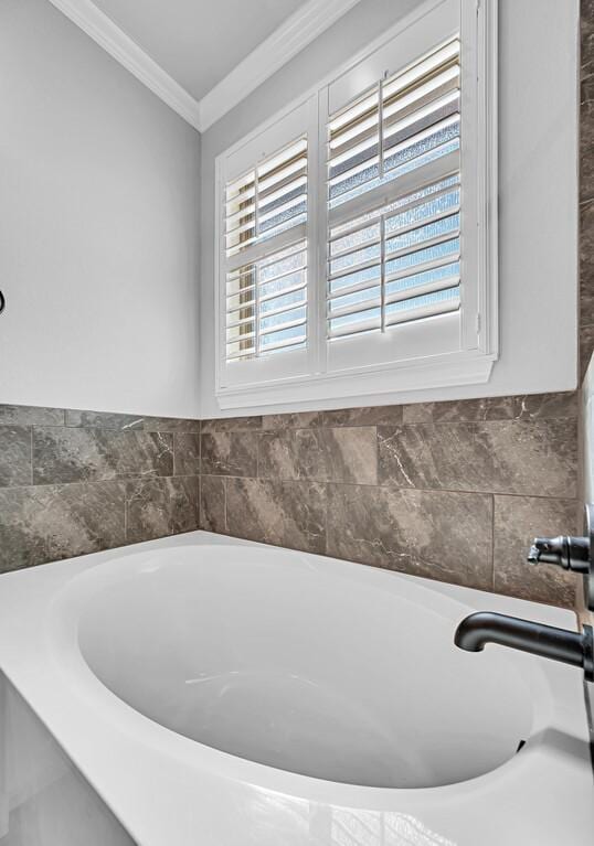 bathroom with crown molding and a tub