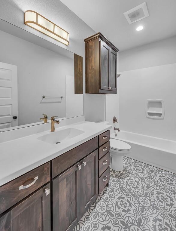 full bathroom featuring tile patterned flooring, vanity,  shower combination, and toilet