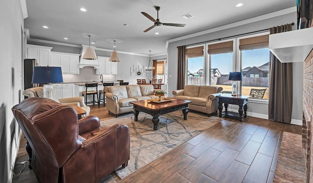 living room with sink, dark wood-type flooring, ornamental molding, and ceiling fan