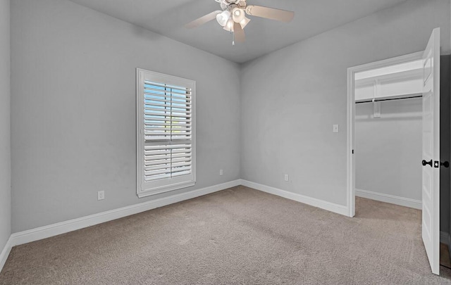 unfurnished bedroom with ceiling fan, light colored carpet, a spacious closet, and a closet