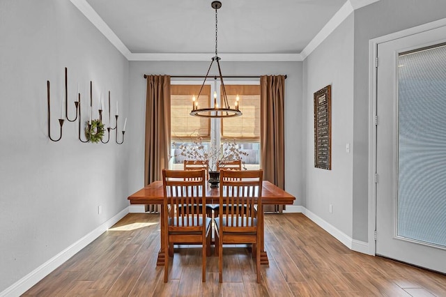 dining area with hardwood / wood-style flooring, crown molding, and a chandelier