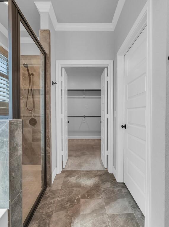 bathroom featuring ornamental molding and a shower with shower door