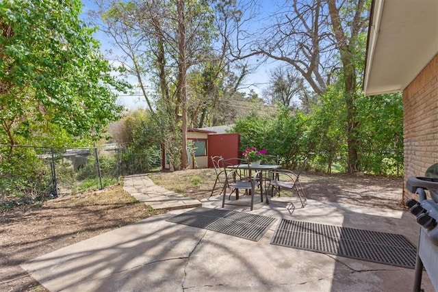 view of patio / terrace with an outbuilding, outdoor dining area, and fence