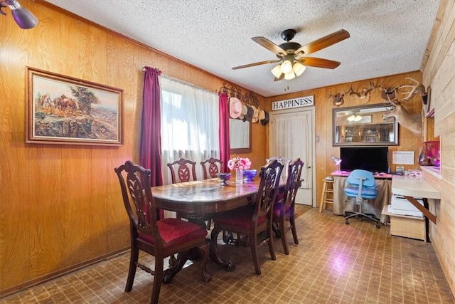 dining space with tile patterned floors, wood walls, a textured ceiling, and a ceiling fan