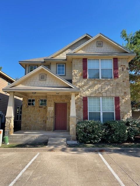 craftsman inspired home with uncovered parking, stone siding, and a porch