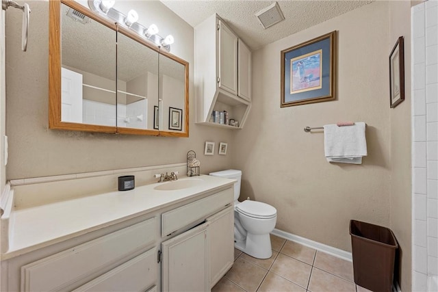 bathroom with tile patterned flooring, vanity, toilet, and a textured ceiling