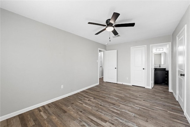 unfurnished bedroom with dark wood-style floors, visible vents, connected bathroom, ceiling fan, and baseboards