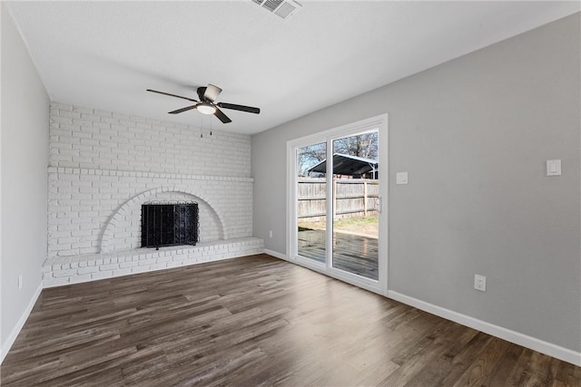 unfurnished living room featuring baseboards, visible vents, a ceiling fan, wood finished floors, and a brick fireplace