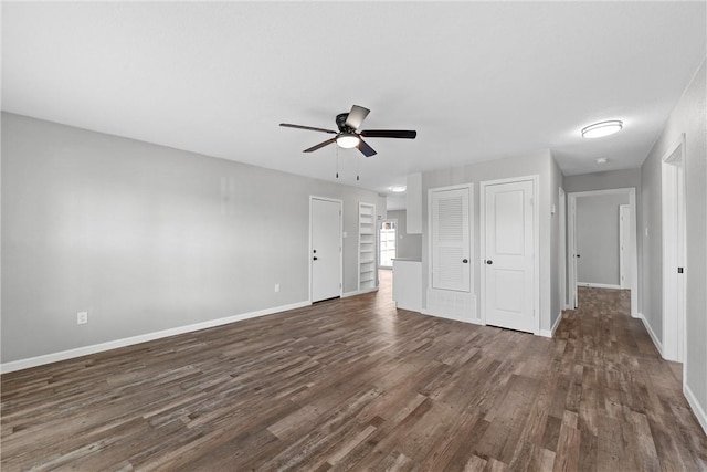 unfurnished bedroom featuring dark wood-style floors, ceiling fan, multiple closets, and baseboards