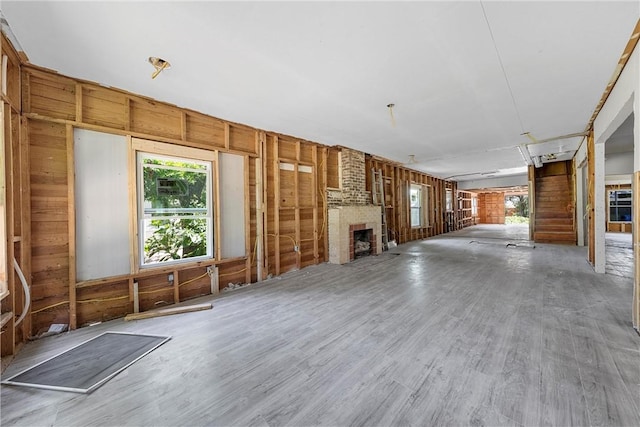 unfurnished living room with a fireplace, hardwood / wood-style floors, and wooden walls