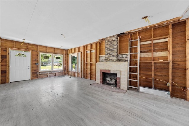 unfurnished living room featuring wooden walls and a fireplace