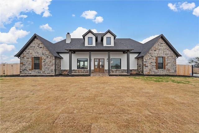 view of front of home featuring stone siding, fence, french doors, and a front yard