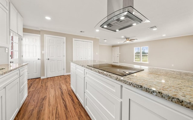 kitchen featuring black electric stovetop, white cabinetry, island range hood, and light stone countertops