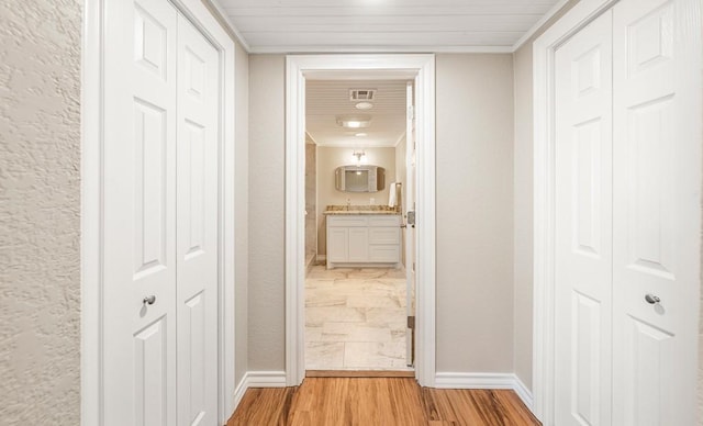 corridor with light hardwood / wood-style floors and ornamental molding