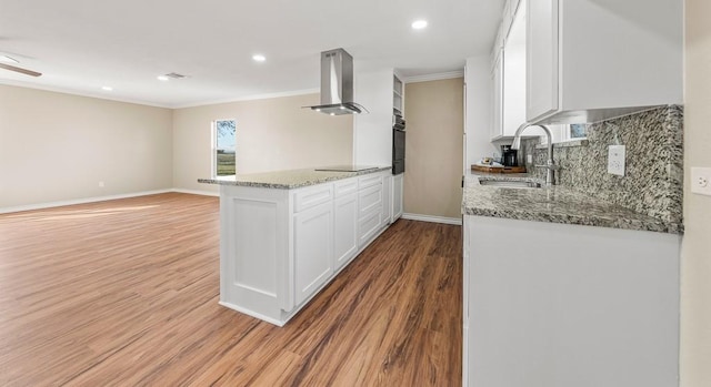 kitchen featuring white cabinets, sink, light wood-type flooring, island range hood, and light stone counters