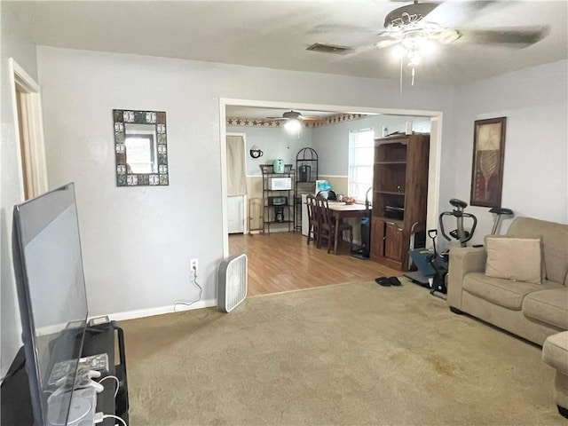 living room featuring a ceiling fan, carpet flooring, visible vents, and baseboards