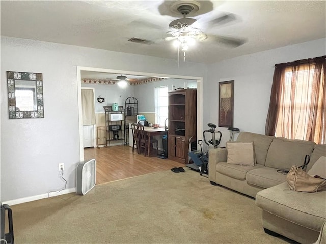 living room with baseboards, ceiling fan, visible vents, and carpet flooring