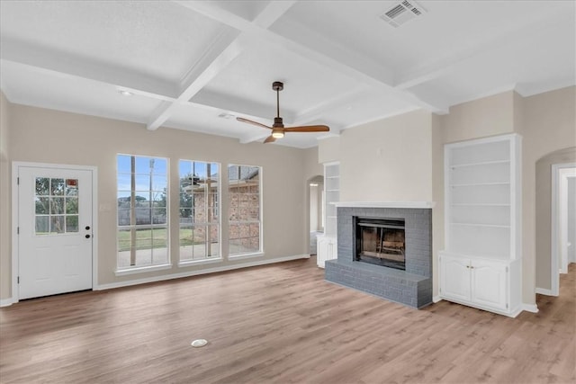 unfurnished living room with a brick fireplace, beamed ceiling, coffered ceiling, light hardwood / wood-style flooring, and built in shelves