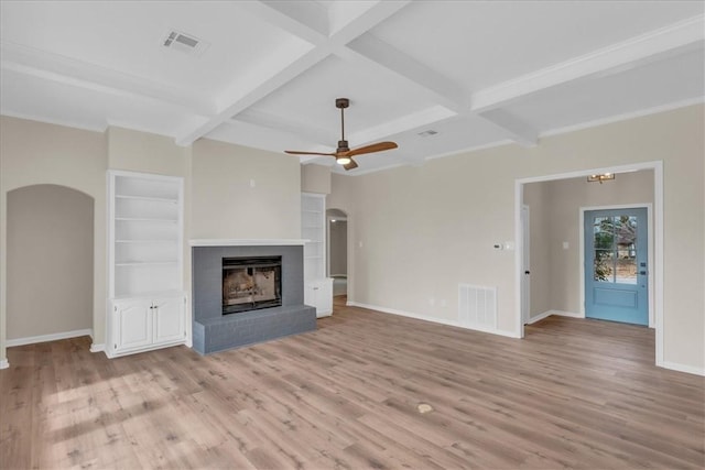 unfurnished living room with ceiling fan, a fireplace, beamed ceiling, light hardwood / wood-style flooring, and built in features