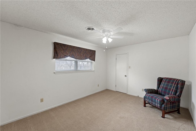 living area with light carpet, ceiling fan, and a textured ceiling