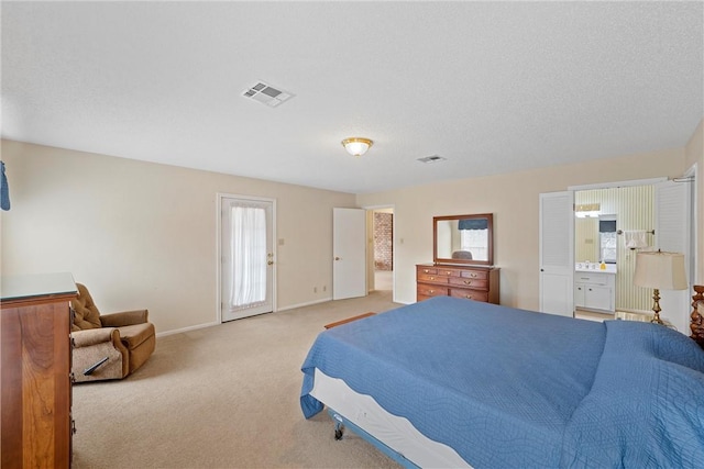 bedroom with light colored carpet, ensuite bath, multiple windows, and a textured ceiling