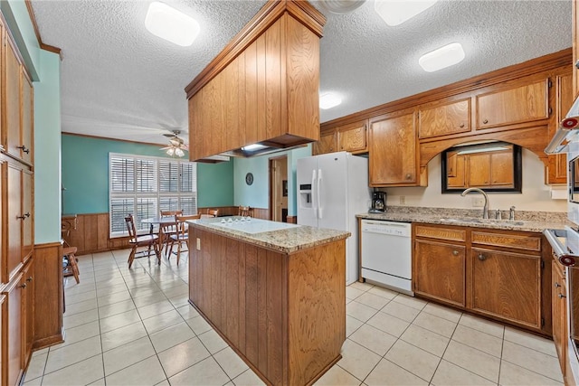 kitchen with sink, light tile patterned floors, ceiling fan, light stone countertops, and white appliances