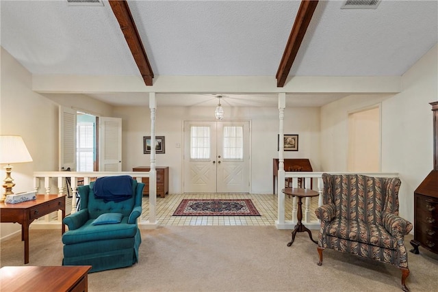 foyer with beamed ceiling, light colored carpet, a textured ceiling, and french doors