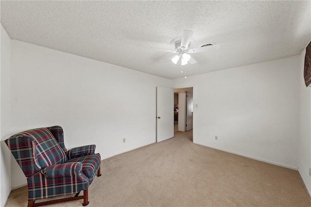 sitting room with ceiling fan, light colored carpet, and a textured ceiling