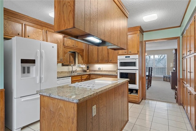 kitchen featuring a center island, light tile patterned floors, white appliances, light stone countertops, and a textured ceiling