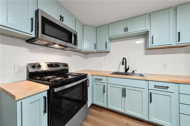 kitchen featuring wooden counters, decorative backsplash, light wood-type flooring, stainless steel appliances, and sink