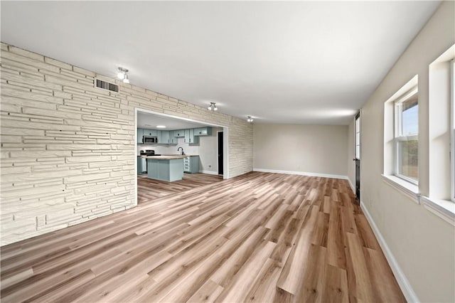 unfurnished living room featuring sink and light hardwood / wood-style floors