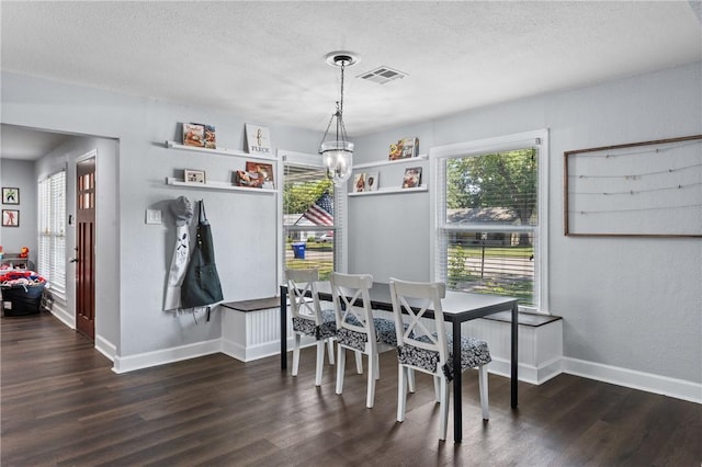 dining space with visible vents, a notable chandelier, a textured ceiling, and wood finished floors