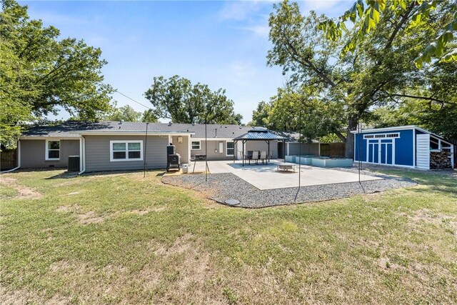 back of property with a patio, an outdoor structure, a yard, a gazebo, and a storage unit