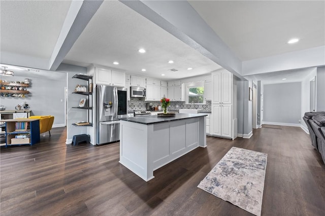 kitchen with decorative backsplash, dark countertops, dark wood-type flooring, stainless steel appliances, and white cabinetry