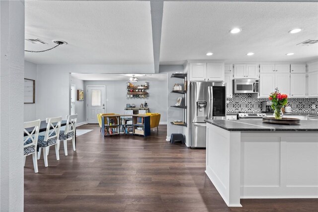 kitchen with dark wood-type flooring, white cabinetry, visible vents, appliances with stainless steel finishes, and decorative backsplash