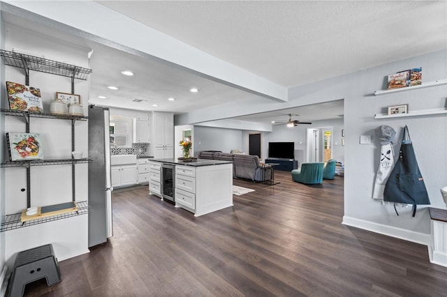 kitchen featuring wine cooler, dark wood-type flooring, dark countertops, and white cabinetry