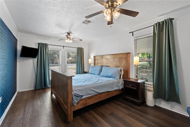 bedroom featuring a textured ceiling, ceiling fan, brick wall, visible vents, and dark wood-style floors