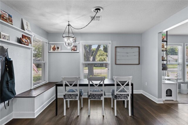 dining space with breakfast area, visible vents, a textured ceiling, and wood finished floors