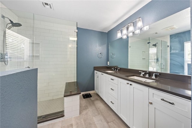 bathroom featuring visible vents, a tile shower, a sink, and wood finished floors