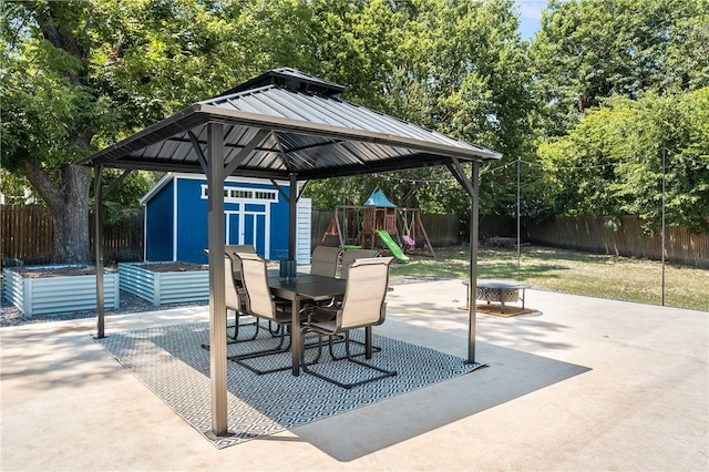 view of patio / terrace featuring a storage shed, a fenced backyard, an outbuilding, outdoor dining area, and a playground